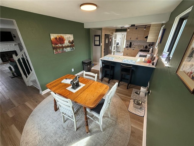 dining room featuring wood finished floors, a stone fireplace, and baseboards