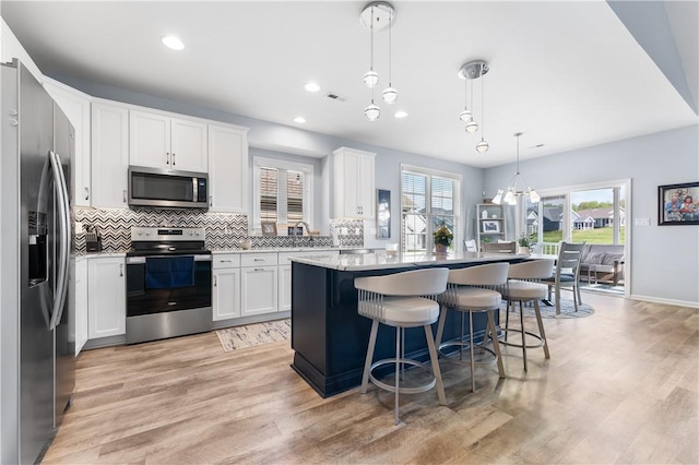 kitchen featuring stainless steel appliances, a center island, tasteful backsplash, light wood-type flooring, and recessed lighting