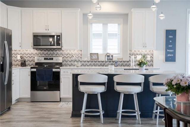 kitchen featuring stainless steel appliances, white cabinets, and backsplash