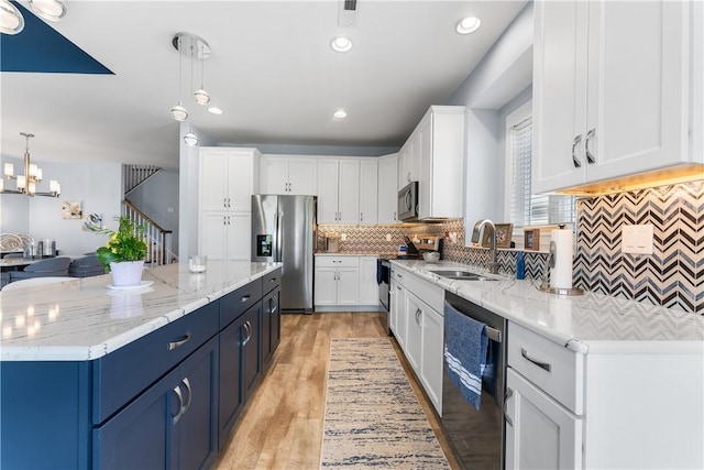 kitchen with stainless steel appliances, a sink, backsplash, white cabinetry, and a center island