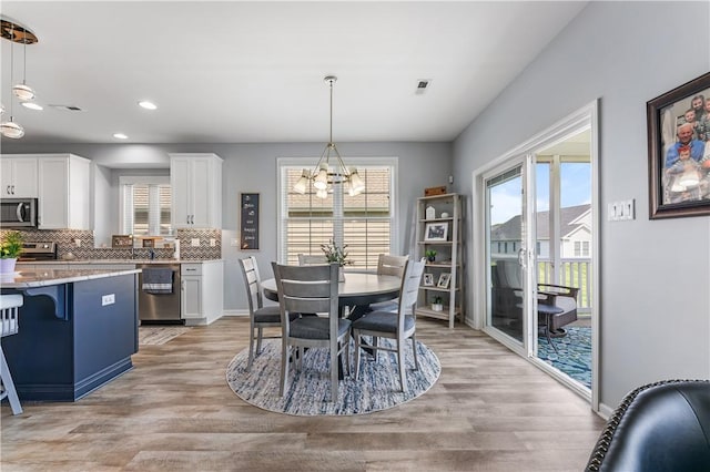 dining area with a chandelier, light wood finished floors, healthy amount of natural light, and recessed lighting