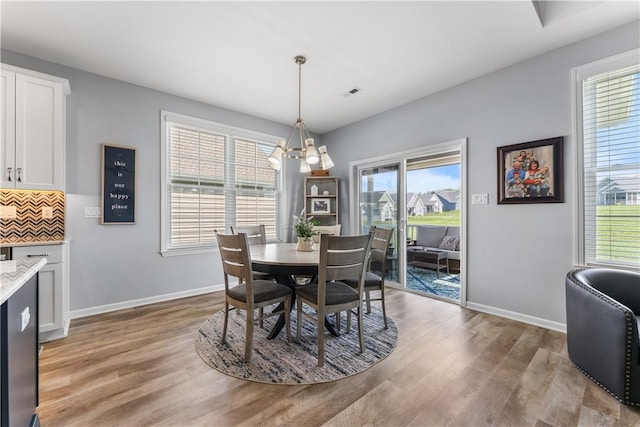 dining space featuring light wood-style floors, plenty of natural light, and a chandelier