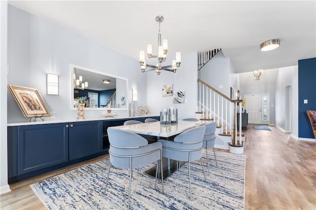 dining area with a chandelier, stairs, light wood finished floors, and baseboards