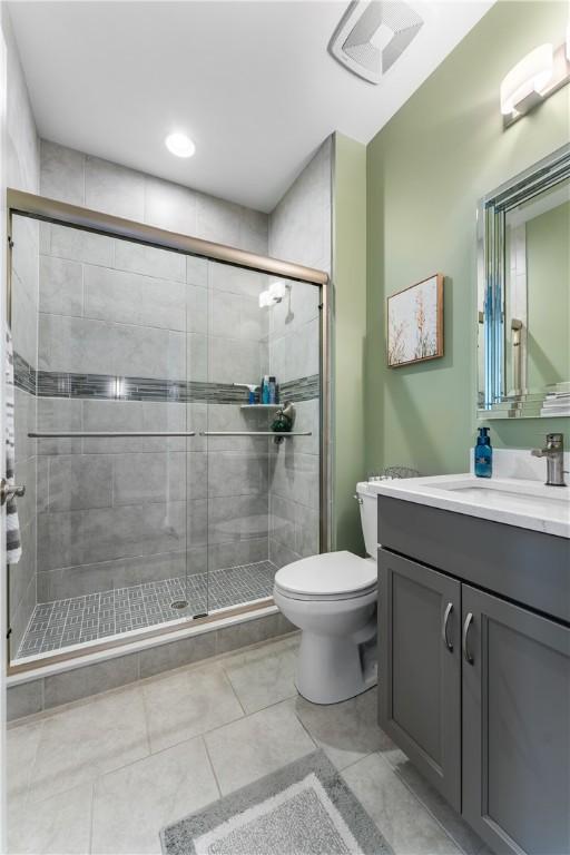 bathroom with toilet, a stall shower, vanity, and tile patterned flooring
