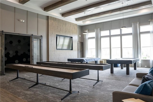 recreation room featuring beam ceiling and a barn door