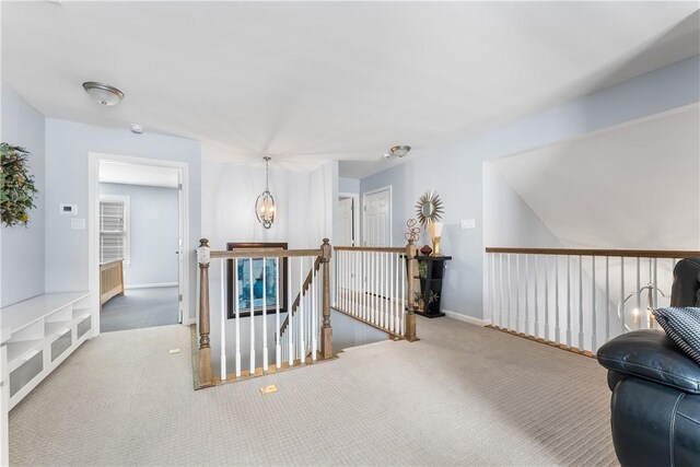 sitting room featuring an upstairs landing, carpet floors, and a chandelier