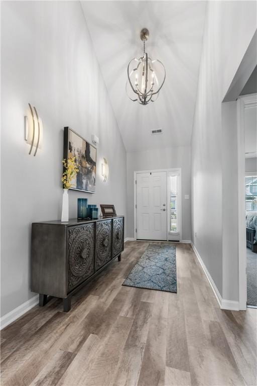 entrance foyer with high vaulted ceiling, a chandelier, plenty of natural light, wood finished floors, and baseboards