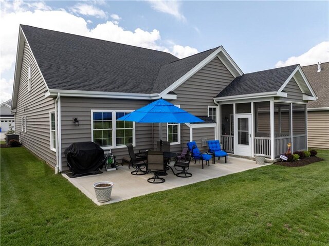 rear view of house featuring a shingled roof, a sunroom, a patio area, and a lawn