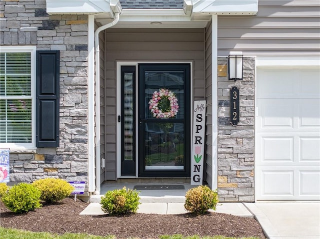 entrance to property featuring stone siding and an attached garage
