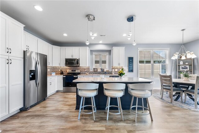 kitchen featuring stainless steel appliances, plenty of natural light, decorative backsplash, light wood-style flooring, and recessed lighting