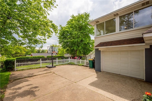 view of property exterior featuring fence, concrete driveway, and an attached garage