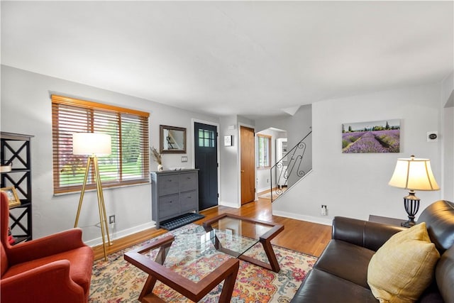 living area featuring plenty of natural light, baseboards, wood finished floors, and stairway