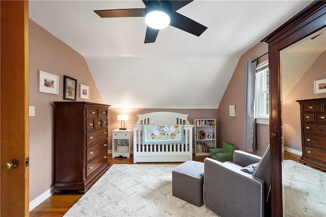 bedroom with vaulted ceiling, wood finished floors, baseboards, and a ceiling fan