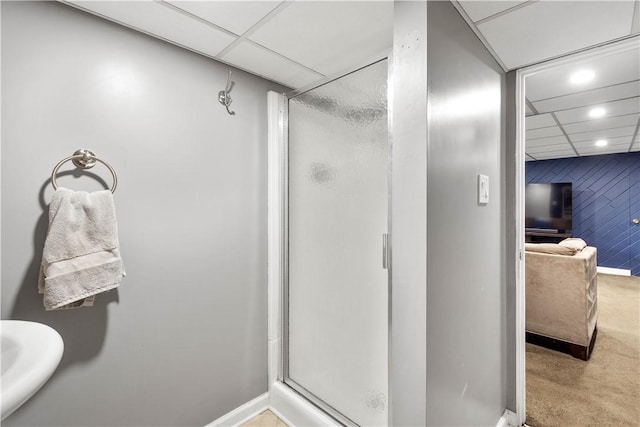 bathroom with a drop ceiling, recessed lighting, a shower stall, and baseboards