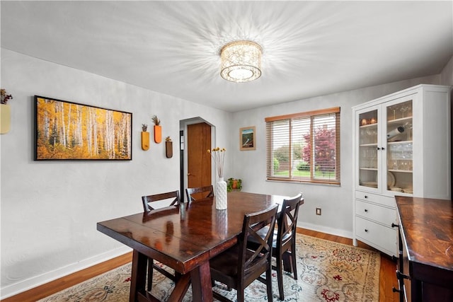 dining room with a chandelier, baseboards, and wood finished floors