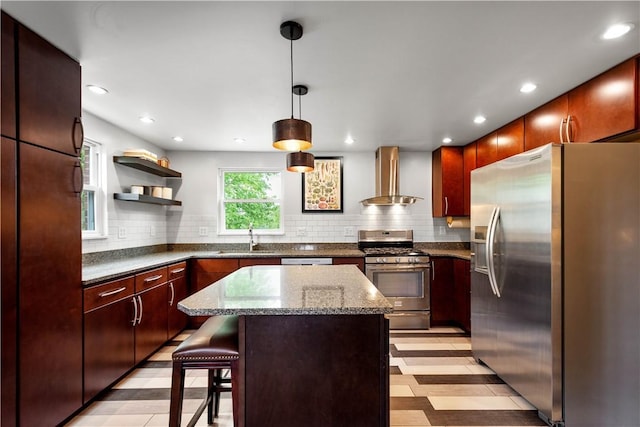 kitchen with stainless steel appliances, wall chimney range hood, a sink, backsplash, and pendant lighting