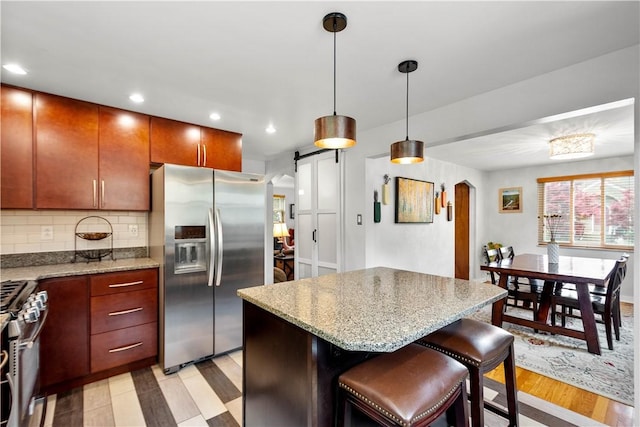 kitchen with stainless steel appliances, a barn door, tasteful backsplash, a kitchen island, and recessed lighting