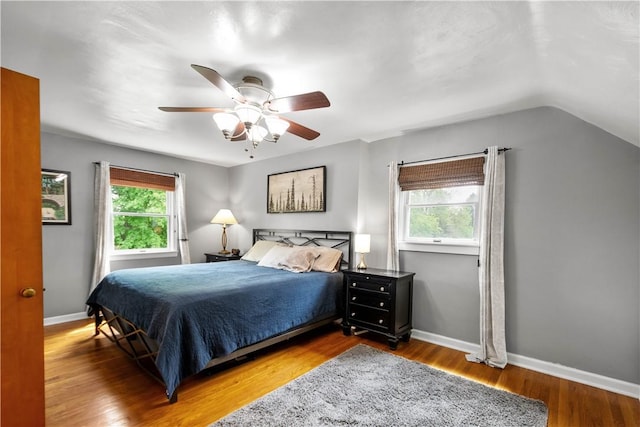 bedroom featuring wood finished floors, lofted ceiling, baseboards, and ceiling fan