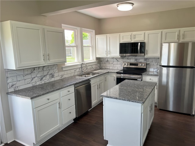 kitchen with appliances with stainless steel finishes, a sink, dark wood-style floors, and white cabinetry