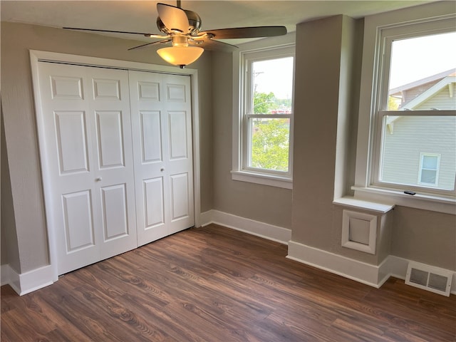 unfurnished bedroom featuring baseboards, dark wood-style flooring, a closet, and ceiling fan