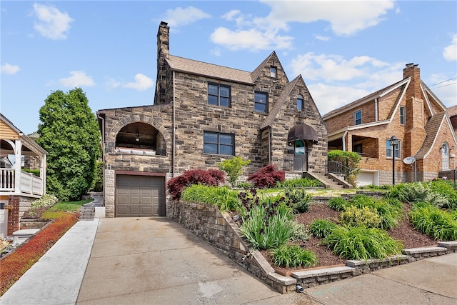 4030 Dalewood St, Brentwood, PA 15227 - tudor-style house with an attached garage, concrete driveway, stone siding, and a chimney
