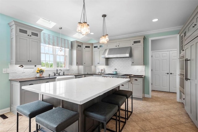 kitchen featuring under cabinet range hood, a breakfast bar area, stainless steel gas stovetop, a center island, and recessed lighting