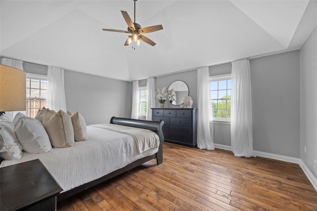 bedroom with lofted ceiling, multiple windows, hardwood / wood-style floors, baseboards, and ceiling fan