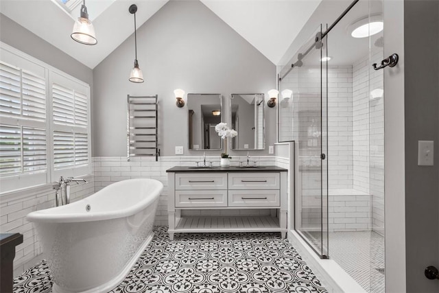 full bath with a stall shower, a freestanding tub, double vanity, tile walls, and a wainscoted wall