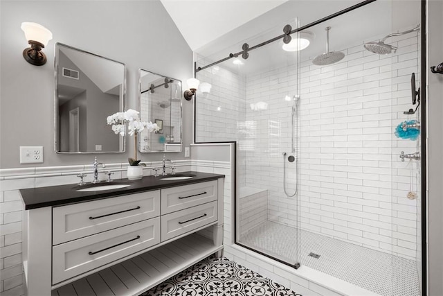 bathroom featuring lofted ceiling, a stall shower, tile patterned floors, and double vanity