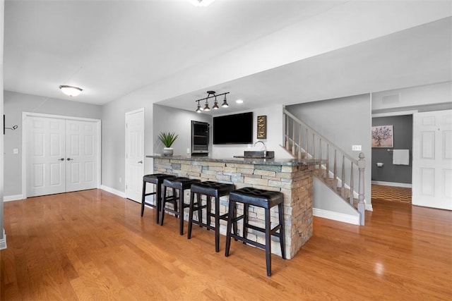 kitchen featuring wood finished floors, baseboards, a kitchen breakfast bar, and a peninsula