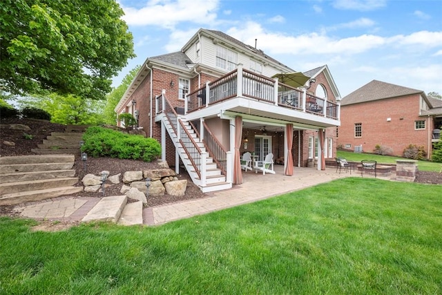 rear view of house featuring stairs, a lawn, a patio, and brick siding