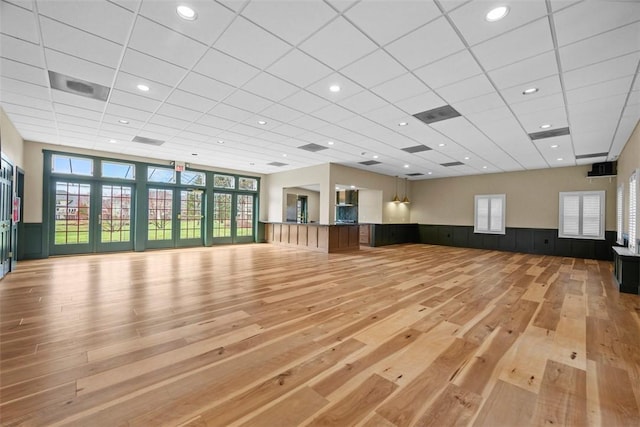 workout area featuring light wood finished floors, wainscoting, plenty of natural light, a drop ceiling, and recessed lighting