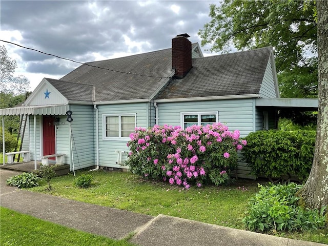 back of property with a chimney, a yard, and a shingled roof