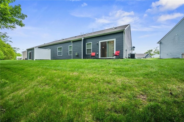 back of house featuring central air condition unit and a lawn