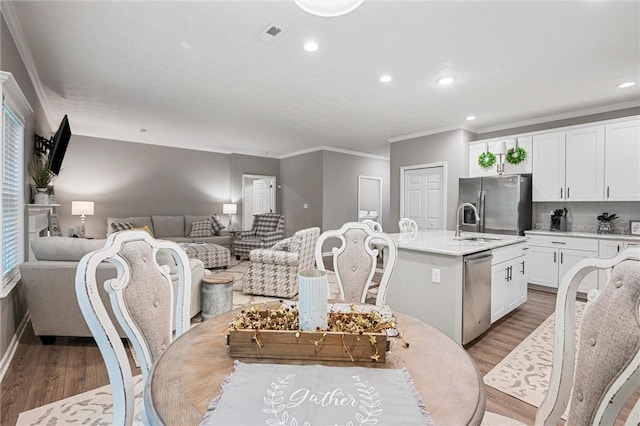 dining room with ornamental molding, light wood-style flooring, recessed lighting, and baseboards