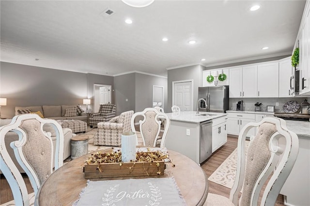 dining area featuring crown molding, recessed lighting, and light wood-style flooring