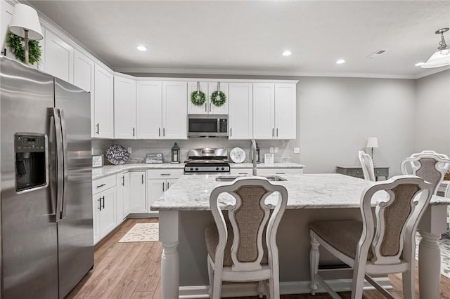kitchen with appliances with stainless steel finishes, a sink, light wood-style flooring, ornamental molding, and white cabinets