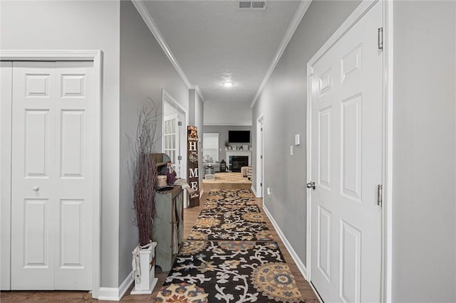 corridor with ornamental molding, baseboards, and wood finished floors