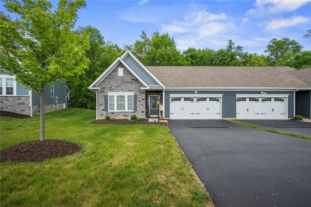 view of front of house featuring a garage, driveway, a front lawn, and stone siding