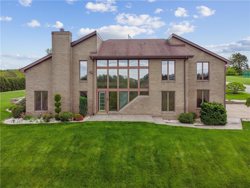 671 Lincrest Dr, North Huntingdon, PA 15642 - back of property with a chimney, a yard, brick siding, and a patio