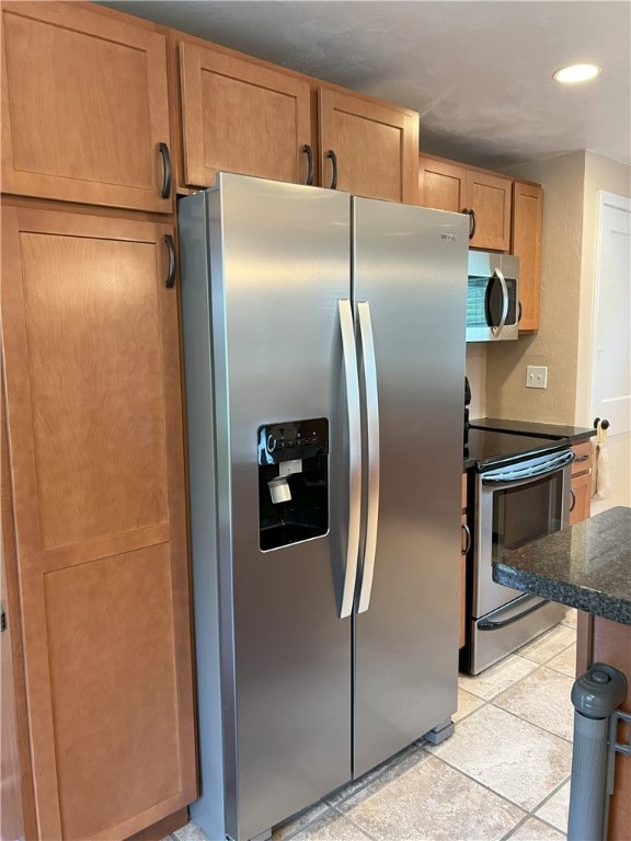 kitchen featuring stainless steel appliances, recessed lighting, dark stone counters, and brown cabinets