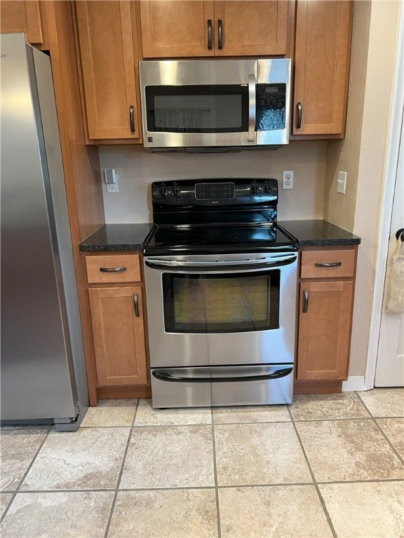 kitchen featuring appliances with stainless steel finishes, brown cabinetry, and light tile patterned floors