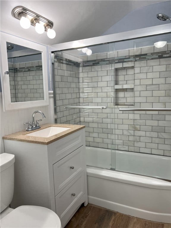 full bath featuring toilet, wood finished floors, vanity, and shower / bath combination with glass door