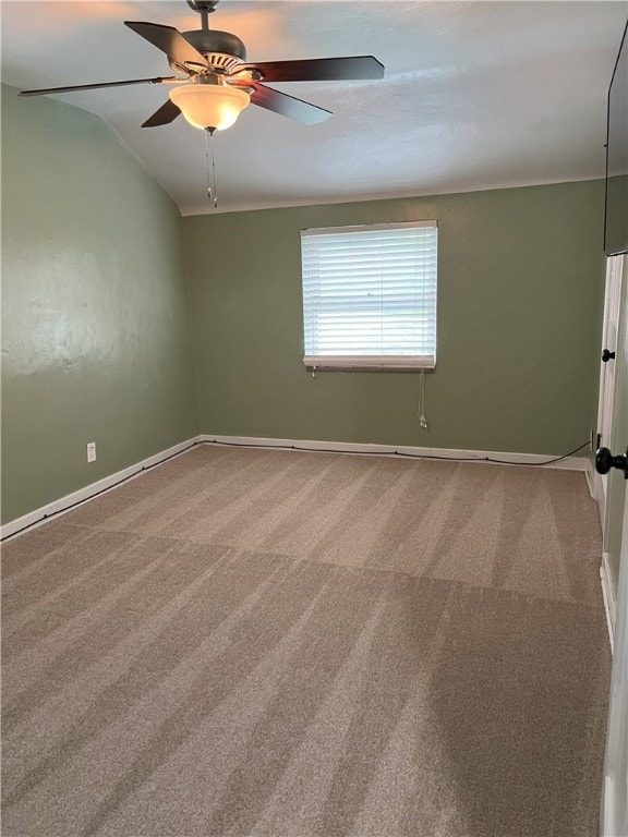 empty room featuring carpet flooring, baseboards, a ceiling fan, and lofted ceiling