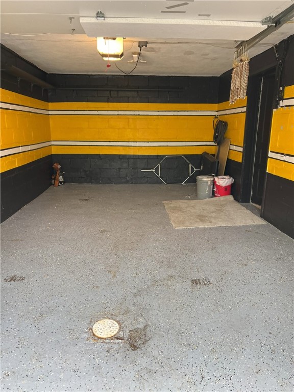 garage featuring concrete block wall and a garage door opener