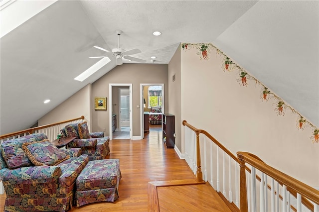 living area with lofted ceiling, a ceiling fan, light wood-style floors, a skylight, and recessed lighting
