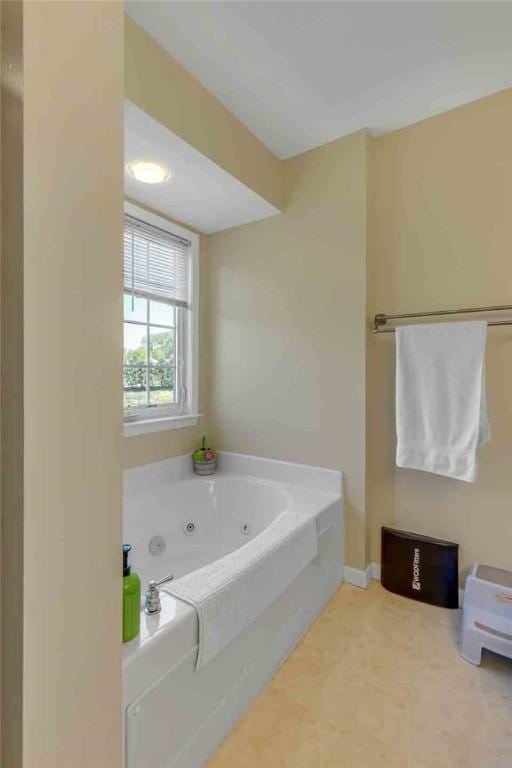 full bathroom with a whirlpool tub and baseboards