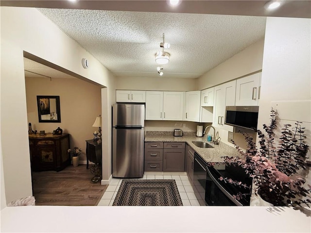 kitchen featuring appliances with stainless steel finishes, a sink, white cabinetry, light countertops, and a textured ceiling