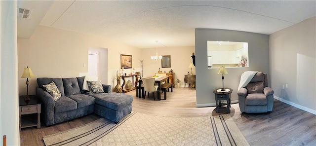 living room featuring wood finished floors, baseboards, and a chandelier