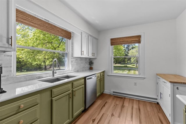 kitchen with green cabinetry, stainless steel dishwasher, a baseboard heating unit, a sink, and light countertops